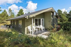 a green cottage with a table and chairs on a porch at 0215-Romo-Vestergardsvej-8 in Høm