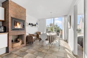 a living room with a fireplace and a table and chairs at 1914-Romo-Blaklokkevej-914 in Høm