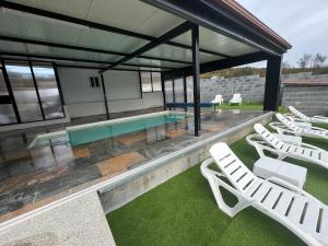 a group of white lounge chairs and a swimming pool at Casa Pepe in Ourense
