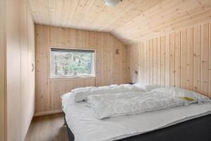 a large bed in a room with wooden walls at 0120-Romo-Smafolksvej-61 in Høm