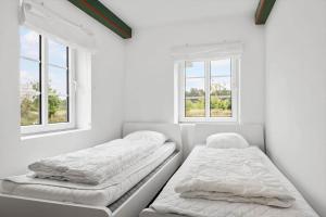 two beds in a white room with two windows at 2804-Romo-Bornholmervej-4 in Høm