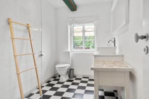 a bathroom with a toilet and a sink and a window at 2804-Romo-Bornholmervej-4 in Høm