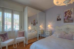 ボルディゲーラにあるCASA GRANDIS Dimora di Charme nel Cuore di Bordigheraのベッドルーム1室(ベッド1台、椅子2脚、鏡付)