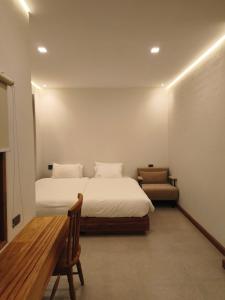 a bedroom with two beds and a bench in it at เดอะมูนไลท์วิลล่าพะเยา in Phayao