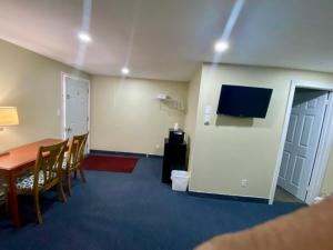 a room with a table and chairs and a television at Kings Inn Orillia in Orillia