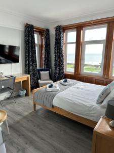 a bedroom with a bed and a tv and windows at The Cairns Leven in Fife