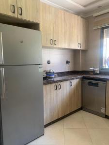 a kitchen with a white refrigerator and wooden cabinets at Résidence sable d or in Mansouria