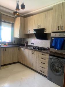 a kitchen with wooden cabinets and a washing machine at Résidence sable d or in Mansouria