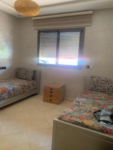 a bedroom with two twin beds and a window at Résidence sable d or in Mansouria