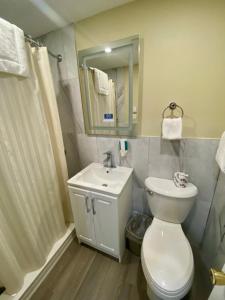 a bathroom with a toilet and a sink and a mirror at Kings Inn Orillia in Orillia +17 photos