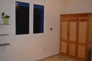 a room with two windows and a wooden cabinet at west wave surf house in Tamraght Ouzdar