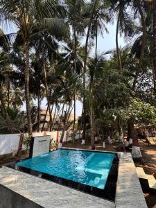 a swimming pool in front of some palm trees at Shree Savali Cottage in Revadanda
