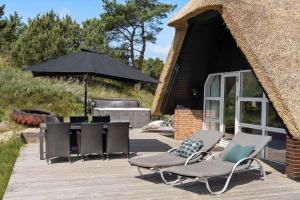 a deck with chairs and an umbrella and a grill at 2600-Romo-Vestergardsvej-18 in Høm