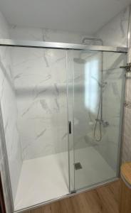 a shower stall with a glass door with a shower at PortoHome Ático in Portomarin +13 photos