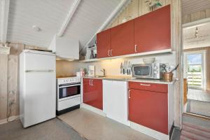 a kitchen with a white refrigerator and red cabinets at 0389-Romo-Vestergade-3-Ap-77 in Høm