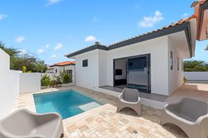 a villa with a swimming pool and a house at Tropilena Resort in Willemstad