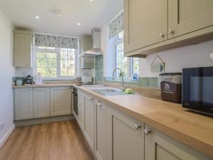 a kitchen with white cabinets and a sink at The Old Smithy in Bridport