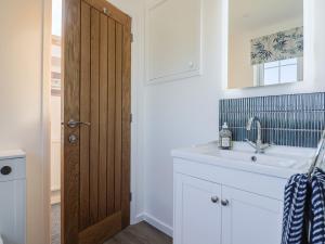 a bathroom with a sink and a wooden door at The Old Smithy in Bridport +25 photos