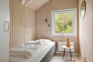 a small bedroom with a bed and a window at 0153-Romo-Julianehab-5 in Høm