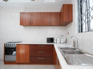 a kitchen with wooden cabinets and a sink at Monroe Luxury Apartments in Kumasi