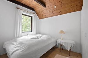 a white bedroom with a bed and a window at 0199-Romo-Lejrbjergvej-32 in Høm