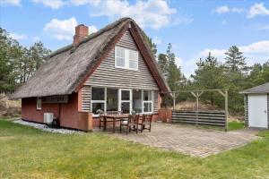 a house with a thatched roof with a patio at 0185-Romo-Rabjergvej-82 in Høm