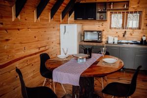a kitchen with a table with chairs and a refrigerator at Refúgio dos Capitéis Cabana in Farroupilha +17 photos