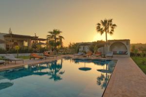 a pool with chairs and palm trees in a backyard at La Villa DUCASSE - Piscine, pétanque, calme à Essaouira in Essaouira
