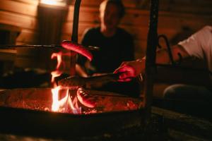 a person cooking food on a grill with fire at Seafront Country house with jacuzzi in Salo