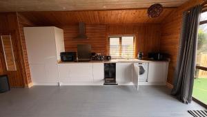 a kitchen with white cabinets in a wooden room at Bryn Bettws Log Cabins Ltd in Port Talbot