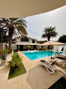 a swimming pool with two chairs and an umbrella at Au Paradis de Jeanne in Ngaparou