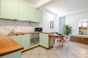 a kitchen with green and white cabinets and a table at Stylish & Colorful Open Space - Sleeps 5 in Manarola