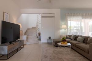 a living room with a couch and a flat screen tv at Villa Isla in Peyia