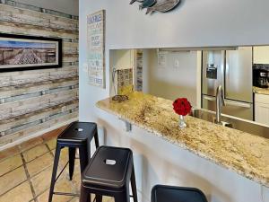 a kitchen with two stools and a counter with a refrigerator at Cozy Coastal Repose in Padre Island +19 photos