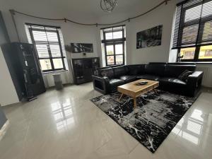 a living room with a black couch and a coffee table at Apartamenty Łuczkowskiego z widokiem na Stary Rynek i Studnie 1 102m2 in Chełm