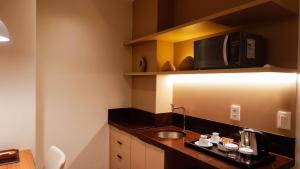 a small kitchen with a sink and a microwave at Soho Plaza Hotel in Brasília