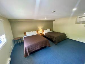 a hotel room with two beds and a window at Kings Inn Orillia in Orillia