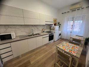 a kitchen with white cabinets and a sink and a table at Le Camere di Don Nicó in Tarquinia