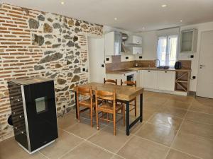 a kitchen with a wooden table and a stone wall at Petite maison design proche centre ville in Cusset