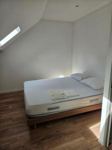 a white bed in a room with a wooden floor at Petite maison design proche centre ville in Cusset