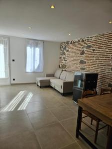 a living room with a couch and a brick wall at Petite maison design proche centre ville in Cusset