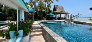 a swimming pool next to a house with the ocean at Villa Sunrise - Golden Beachfront in Nathon Bay