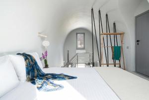 a white bed with a blue blanket on top of it at MelivOia - Sunset Jacuzzi Villas in Foinikiá +32 photos