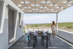 a woman standing on the balcony of a house at MelivOia - Sunset Jacuzzi Villas in Foinikiá