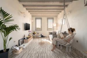 a woman sitting in a hammock in a living room at MelivOia - Sunset Jacuzzi Villas in Foinikiá