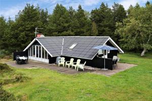a building with a deck with chairs and an umbrella at 0161-Romo-Ejnar-Mikkelsensvej-4 in Høm