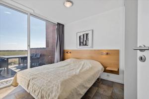 a bedroom with a bed and a balcony at 1170-Romo-Gulirisvej-170 in Høm