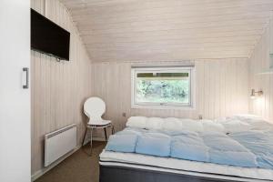 a bedroom with a large bed and a chair at 0019-Romo-Moritzvej-12 in Høm