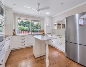 a kitchen with white cabinets and a stainless steel refrigerator at Lamington Cottage in The Range