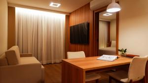 a room with a table and chairs and a television at Soho Plaza Hotel in Brasília